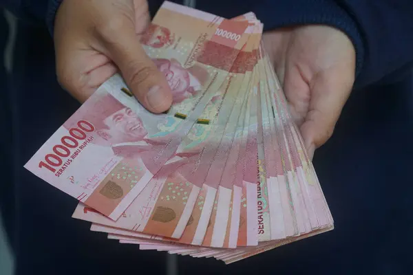 stock image Indonesian rupiah banknote held by a woman, 100,000 rupiah. Focus selected