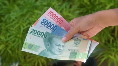 Endonezya parası, 20.000, 50.000 ve 100.000 rupi, bir kadının elinde tutuluyor. Seçilene odaklan