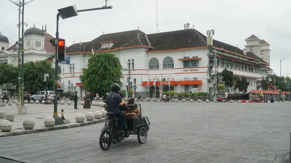 stock image The rickshaw stops at a traffic light with a post office building in the background