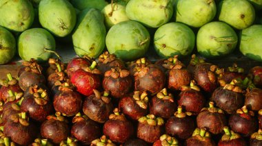 Odaklanmamış fotoğraf - Bazı olgun mangosen meyveleri koyu kırmızı ve bulanık mango arkaplanlı.
