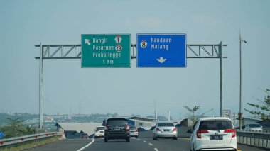 Trans Java toll road at noon. There are signs for the city of Bangil, Probolinggo, Pandaan, Pasuruan, Malang clipart