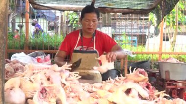 Bir tavuk kasabı tavuk eti kesip tartıyor.