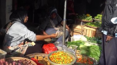 Sabahları geleneksel pazarda tofu, baharat ve sebze satan bir kadın. Alıcı ödeme yapıyor.