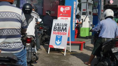 Motosikletler, bir Pertamina benzin istasyonunda sübvansiyonlu benzinle doldurulmak için kuyruğa giriyor.