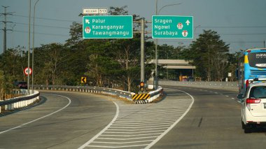 Trans Java toll road at noon. There are signs for the city of Tawangmangu, Ngawi, Sragen, Karanganyar, Surabaya clipart