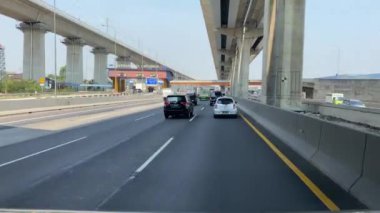 Jakarta 'da otoyolda giden araçlar var. Yükseltilmiş bir paralı yol ve üzerinde bir demiryolu hattı var.
