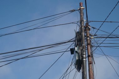 Elektrik kabloları ve telekomünikasyon kabloları demir direklerde kaotiktir. Mavi gökyüzü arkaplanı