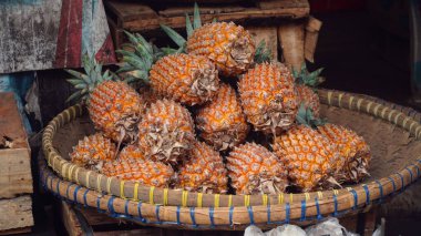 Bambu sepetinde olgun ananas meyvesi yığını. Seçilene odaklan