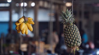 Muz ve ananas iplerle asılır. Odaklanma seçildi. Bulanık arkaplan