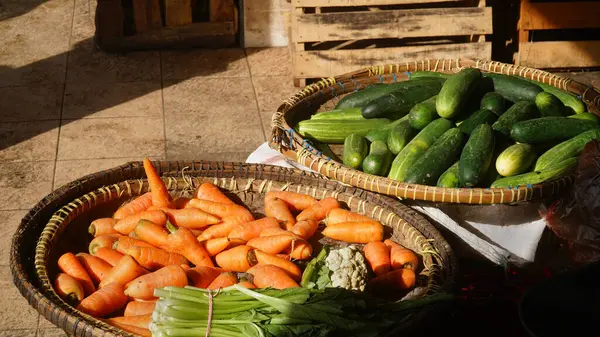 Salatalıklar ve havuçlar bambu sepetlerinde geleneksel bir pazarda güneş ışığına maruz kaldı. Seçilene odaklan