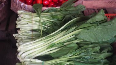 Geleneksel bir markette bambu sepetinde hardal yeşillikleri ve domatesler. Seçilene odaklan