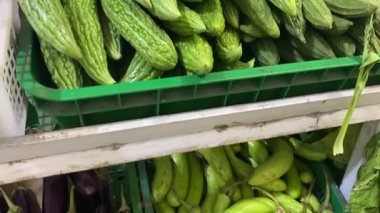 Market rafında çeşitli sebzeler. Acı kavun, patlıcan, domates ve lahana var.