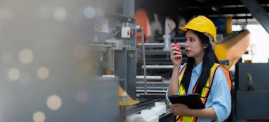 Kadın bir ustabaşı ya da mühendis fabrikada çalışmak için telsiz kullanıyor..