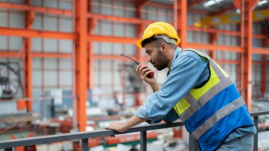 Erkek bir ustabaşı ya da mühendis fabrikada çalışmak için telsiz kullanıyor..