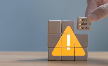 Developer programmer holding a wooden cube with warning triangle sign for notifying error found error and maintenance concept.	