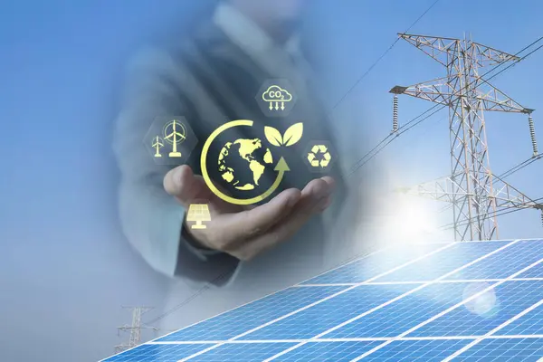 İş adamının elinde fotovoltaik sistemdeki güneş panelleri, temiz enerji, yüksek voltaj kulesi üzerindeki yeşil bitki simgesi var. temiz enerji kavramı