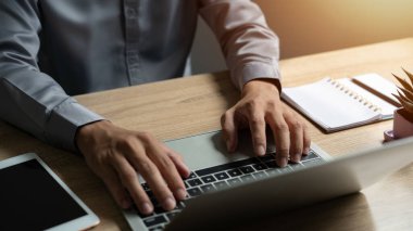 Bir adam dizüstü bilgisayarında dizüstü bilgisayar ve saksı bitkisiyle yazı yazıyor. Verimlilik kavramı ve adam bilgisayarında çalışırken odaklanma