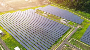 Yeşil bir alanda bir güneş paneli alanı gösterilir. Paneller bir ızgara desen içinde düzenlenir, her bir sıra panel nex 'e paralel olur