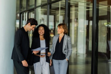 İş kıyafetleri içinde bir grup insan binanın dışında durdu. Gülümseyen ve belgelerini tutan sahne olumlu ve profesyonelceydi..