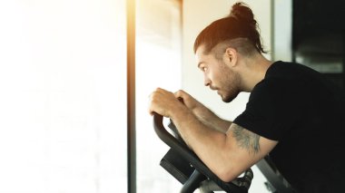 Bir adam sabit bir bisiklette oturur. Ve ileriye baktığında, yorgundu..