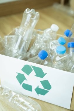 Üzerinde geri dönüşüm işareti olan plastik şişelerle dolu bir kutu. Sahne, çevresel farkındalık ve geri dönüşümün önemidir.