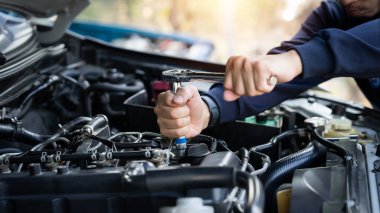 Bir tamirci bir araba motoru üzerinde çalışıyor. Odaklanma ve konsantrasyon kavramı. Tamirci, motoru tamir etmek için ingiliz anahtarını dikkatlice kullanır..
