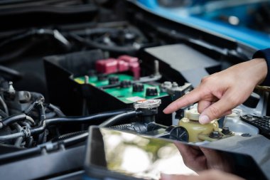 Bir tamirci arabanın radyatörünü işaret ediyor. Radyatör arabanın sol tarafında.