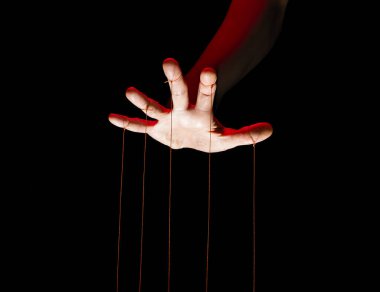 Siyah arka planda her parmağında iplerle kuklacı elleri.