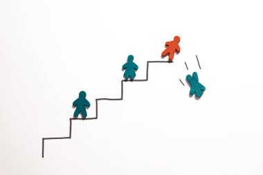 Tahta bir figür, başka bir figürü kariyer merdiveninin tepesinden aşağı iter..