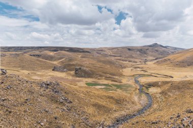 Sonbahar mevsiminde dağların karlı manzarası. Güneşli bir günde sarı bitki örtüsü. Bulutlar ve mavi gökyüzü.