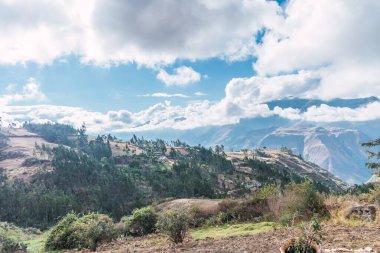 Peru And Dağları 'nda bulutlar ve mavi gökyüzü ile güneşli bir günde karlı dağlar ve yeşil bitki örtüsüyle çevrili gönderedo.
