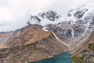 Peru cusco 'nun And Dağları' ndaki Humantay gölünde karla kaplı bulutlarla çevrili dağlar.