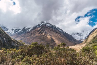 Peru cusco 'nun And Dağları' ndaki Humantay gölünde karla kaplı bulutlarla çevrili dağlar.
