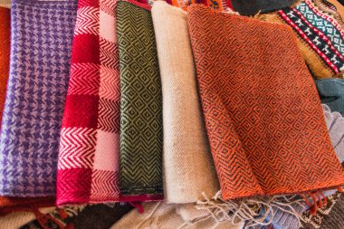 El yapımı, alpaka lifiyle örülmüş çok renkli başlık. Atalarından kalma tasarımlar ve çarpıcı renklerin geometrik figürleri. Masaya yerleştirilmiş beyaz masa örtüsü, doğal ışıkla aydınlatılmış.