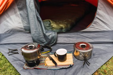 Turuncu çadır arka planda kamp malzemesi. And Dağları 'nın doğal ışıklarıyla aydınlatılmış yeşil çimenler.