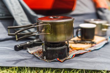 Turuncu çadır arka planda kamp malzemesi. And Dağları 'nın doğal ışıklarıyla aydınlatılmış yeşil çimenler.