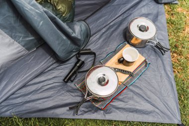 Turuncu çadır arka planda kamp malzemesi. And Dağları 'nın doğal ışıklarıyla aydınlatılmış yeşil çimenler.