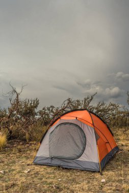 Andes sıradağlarındaki turuncu dağlık çadır fırtına bulutları ve ağaçlarla çevrili.