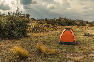 Andes sıradağlarındaki turuncu dağlık çadır fırtına bulutları ve ağaçlarla çevrili.