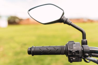 Güneşli bir günde siyah motosiklet dikiz aynası ve motosiklet gidonu.