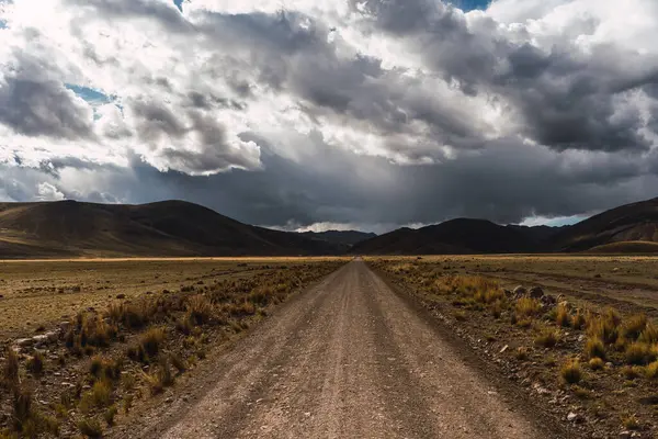Peru And Dağları 'ndaki kirli yolda mavi bir gökyüzü ve gün batımında gri fırtına bulutları