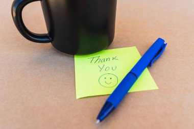 Teşekkür notu. Üzerinde, kahve fincanı arkaplanı olan mavi kalemle yazılmış bir teşekkür notu.