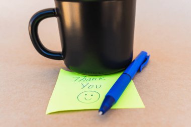 Teşekkür notu. Üzerinde, kahve fincanı arkaplanı olan mavi kalemle yazılmış bir teşekkür notu.