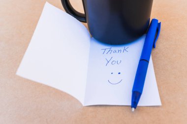 Teşekkür notu. Üzerinde, kahve fincanı arkaplanı olan mavi kalemle yazılmış bir teşekkür notu.