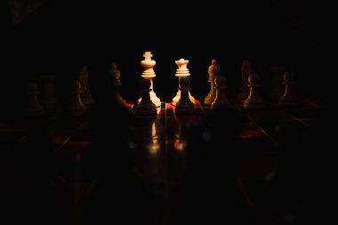 Siyah arkaplanı olan kırmızı ve siyah bir tahtada satranç taşları