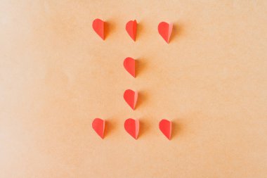 Bej bir yüzeyde iki kağıt kalp ve daha küçük kalp, aşk konsepti..