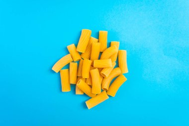 Mavi bir yüzey üzerinde ahşap bir kaşıkta erişteler ve mutlu ve hüzünlü ifadeleri olan bir doğrama tahtası.