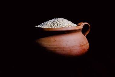 Eski bir seramik kasede renkli bir kumaşın üzerinde siyah bir kaşık olan kinoa.