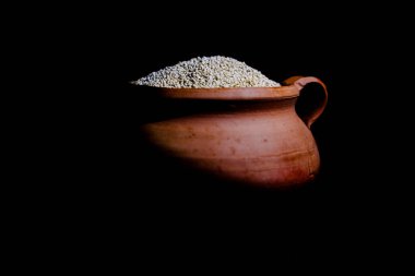 Eski bir seramik kasede renkli bir kumaşın üzerinde siyah bir kaşık olan kinoa.