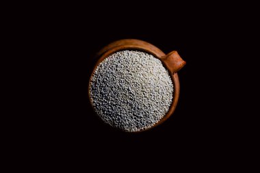 Eski bir seramik kasede renkli bir kumaşın üzerinde siyah bir kaşık olan kinoa.